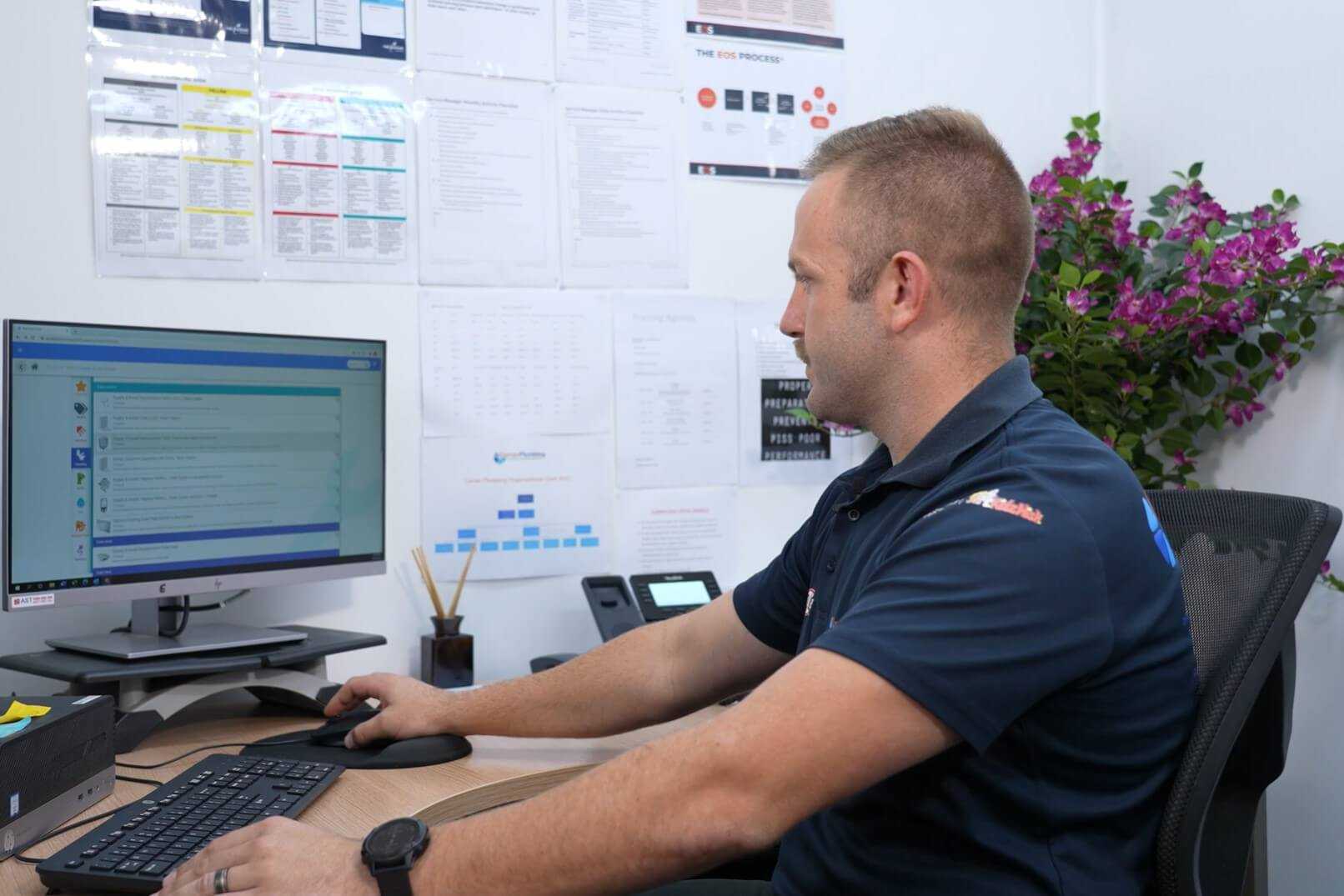 Tradie sitting in front of computer screen working on FlatRateNOW software Tradie sitting in front of computer screen working on FlatRateNOW software