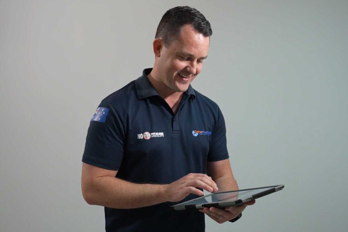 Plumber wearing navy top looking at FlatRateNOW on a tablet Plumber wearing navy top looking at FlatRateNOW on a tablet